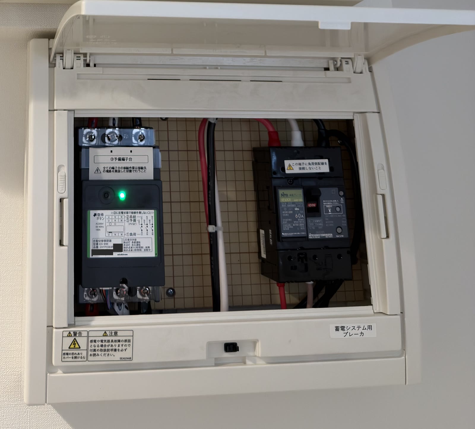 蓄電システム用ブレーカと書かれた白い箱を開けたところ。中に自動切替開閉器と漏電ブレーカが入っている
